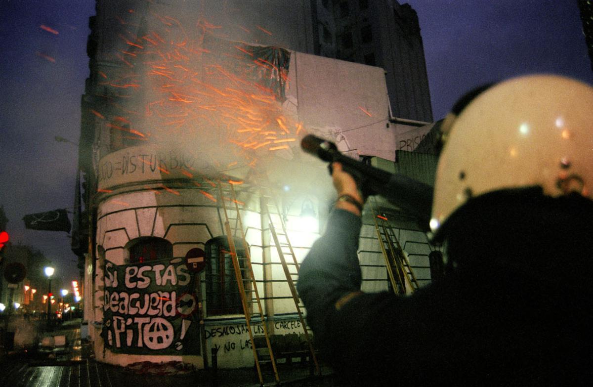 Un policía dispara su escopeta de pelotas de foam durante el desalojo del Cine Princesa en 1996. 