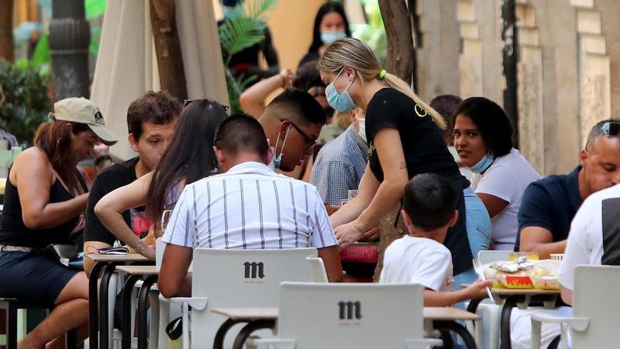 Una camarera atiende a unos clientes en una terraza.