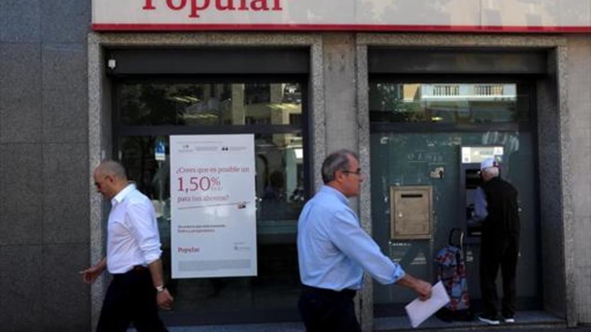 Un cliente usa un cajero automático en una oficina del Banco Popular en Madrid.