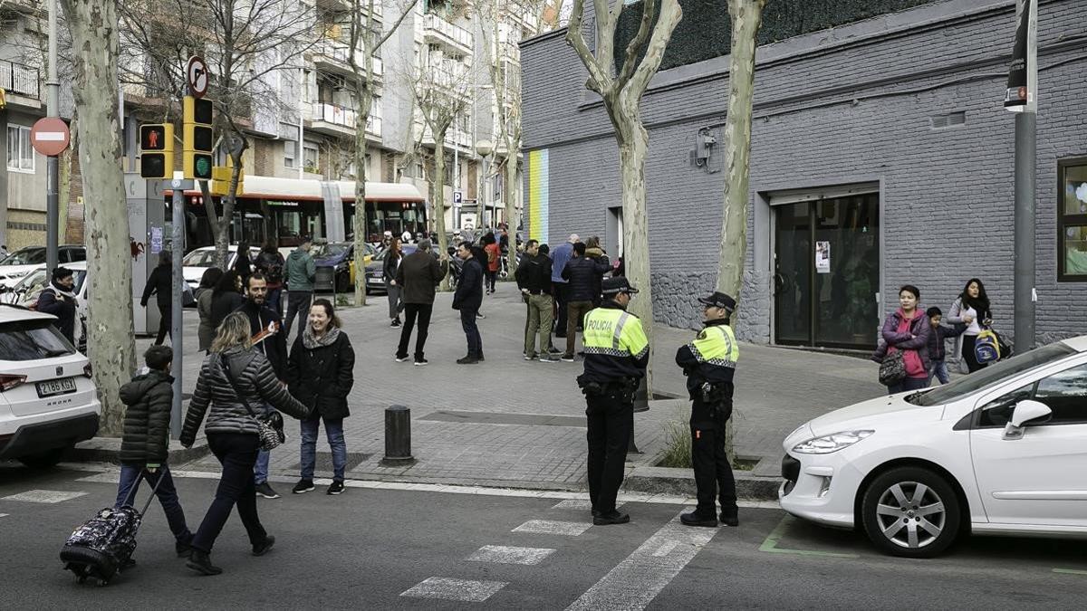 Dos agentes de la Guardia Urbana custodian la entrada de los alumnos del Joan Roca de Guipúscoa, esta mañana