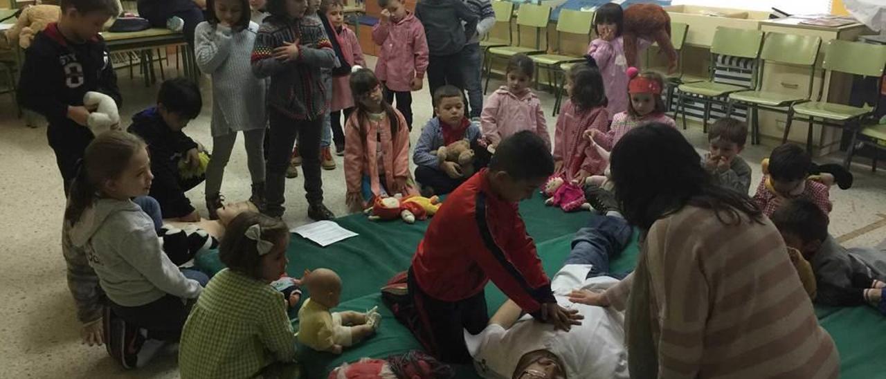 Los alumnos del colegio público Julio Rodríguez Villanueva de Villamayor ensayan la reanimación cardiopulmonar con el pediatra del centro de salud de Infiesto José David Herrero y la enfermera Cruz Gutiérrez.