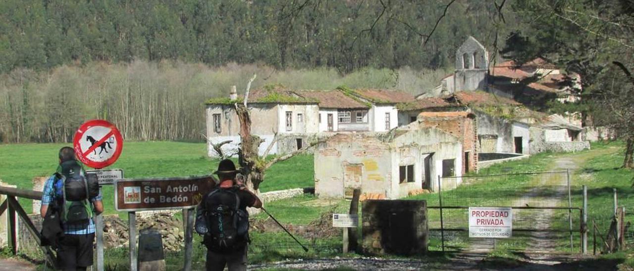 Dos peregrinos, ayer, a la entrada de la finca de San Antolín de Bedón, con la iglesia al fondo.