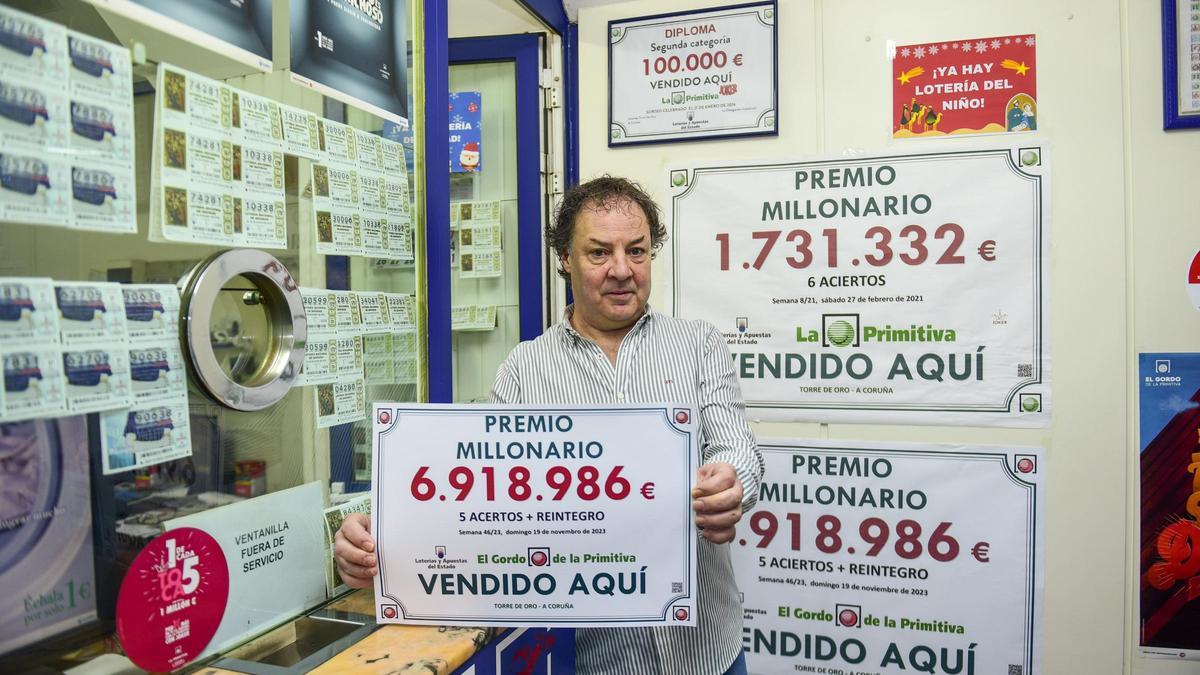 El responsable de la administración de la calle de la Torre, Jorge Pérez, posa hoy con el cartel del premio millonario del Gordo de la Primitiva.