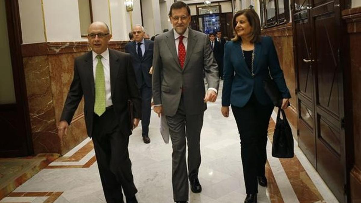 El ministro de Hacienda, Cristóbal Montoro; el presidente del Gobierno, Mariano Rajoy, y la ministra de Trabajo, Fátima Báñez, este 13 de marzo, en los pasillos del Congreso. REUTERS / SUSANA VERA