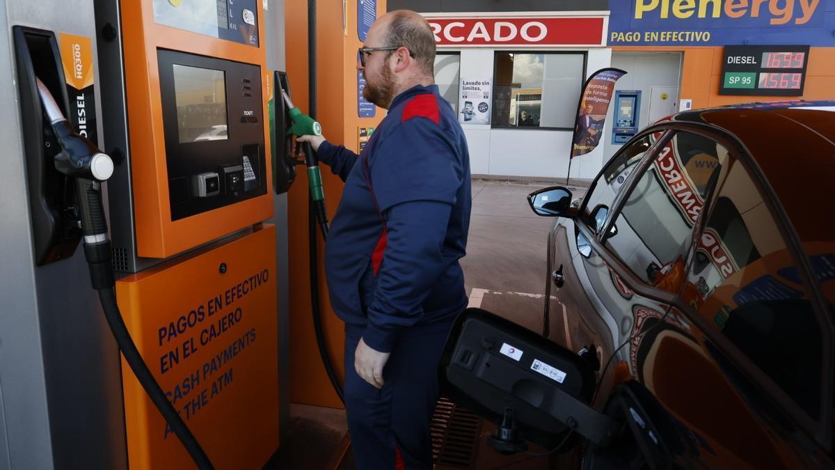 El empleado de una gasolinera de Cartagena toma la manguera para llenar el depósito de un vehículo.