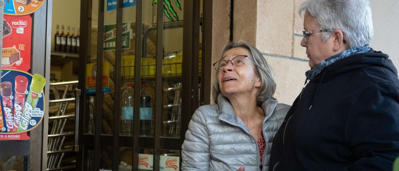 Carla Rodríguez, junto a una vecina, a las puertas del comercio que cerró hace diez días. |