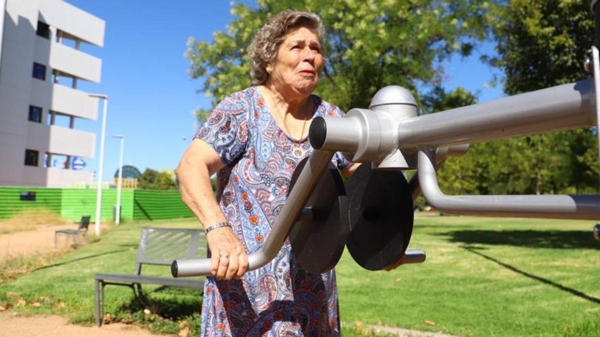 Una mujer mayor utilizando una de las máquinas del nuevo parque cardiosaludable instalado junto al centro de mayores de Huerta de la Reina.