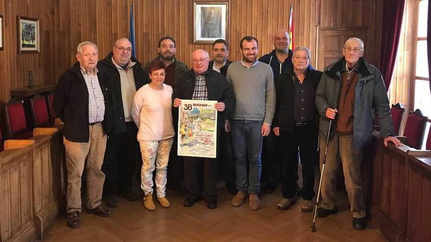 El acuarelista Valentín del Fresno -en el centro- muestra el cartel del 38.º Descenso del Río Piloña, rodeado de autoridades, ayer en Infiesto.