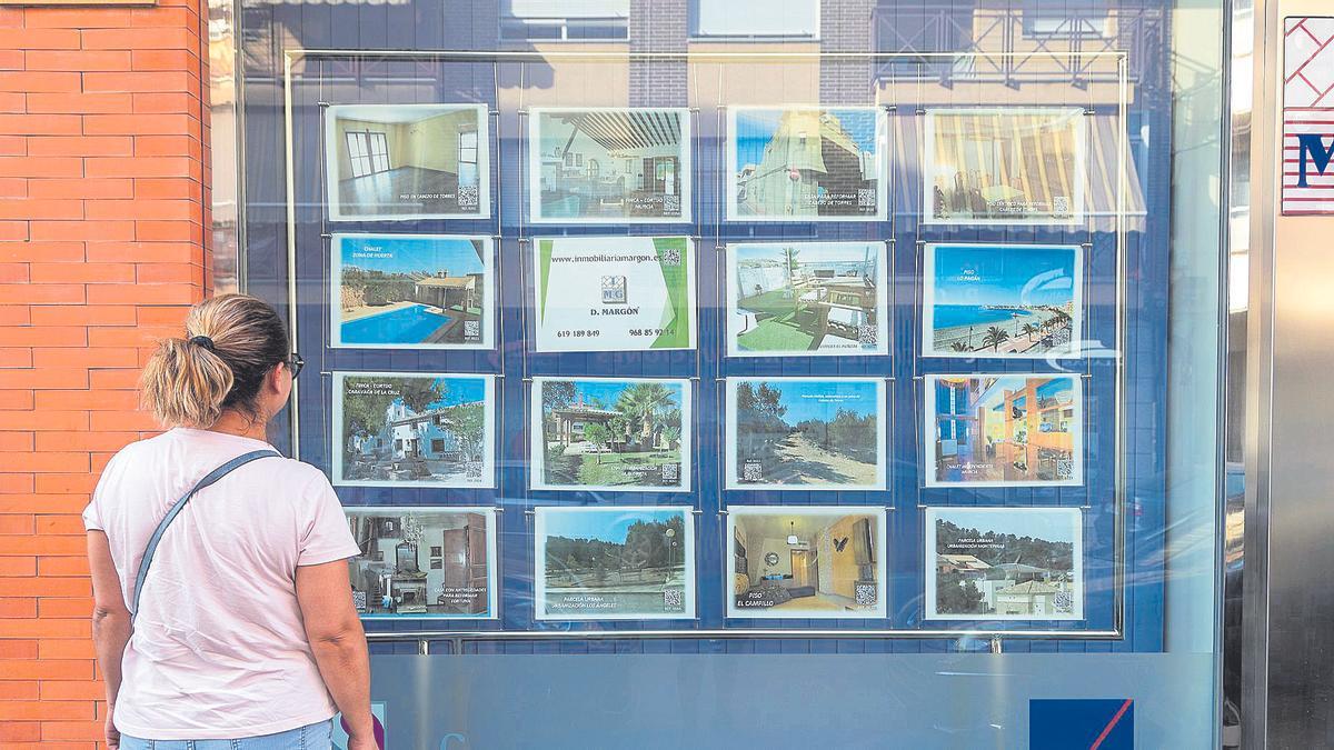 Una mujer contempla los anuncios de pisos en una inmobiliaria en Murcia