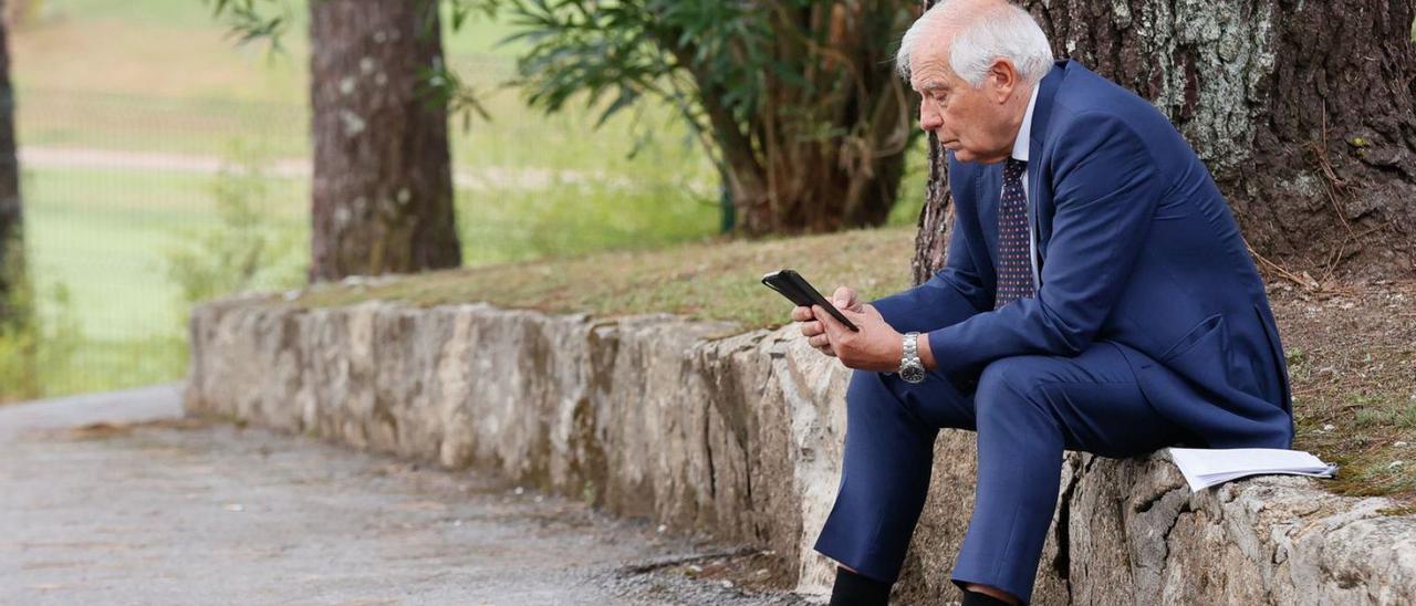 Borrell consulta su teléfono en unos jardines antes de participar en el IV Foro La Toja.