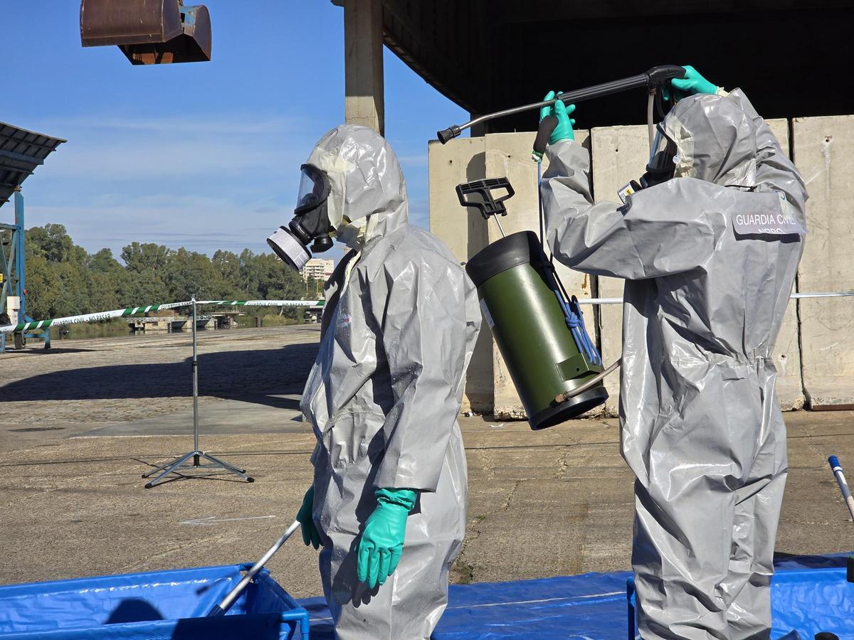 Un agente de la Guardia Civil desinfectando a otro durante el simulacro realizado en el Puerto de Sevilla.