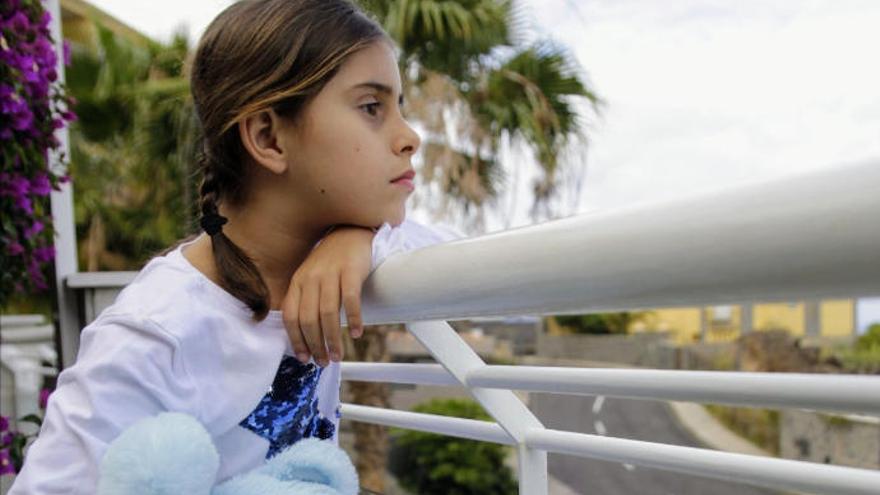 Una niña se asoma a la terraza de su casa en Santa Cruz a la espera de poder salir mañana a pasear.