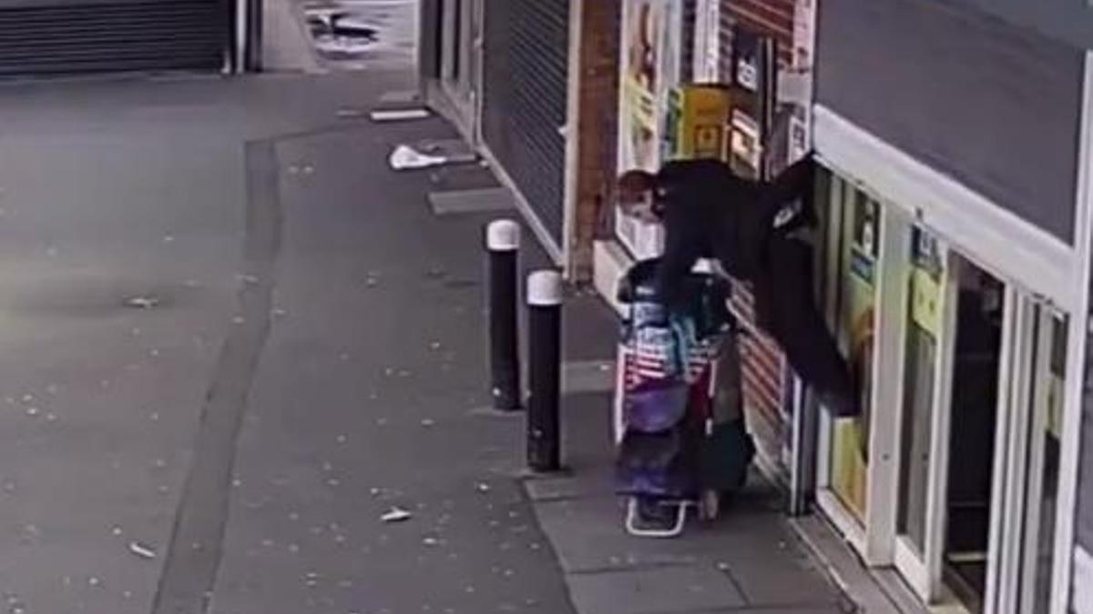 Momento en el que una mujer se queda atrapada en una persiana de un supermercado