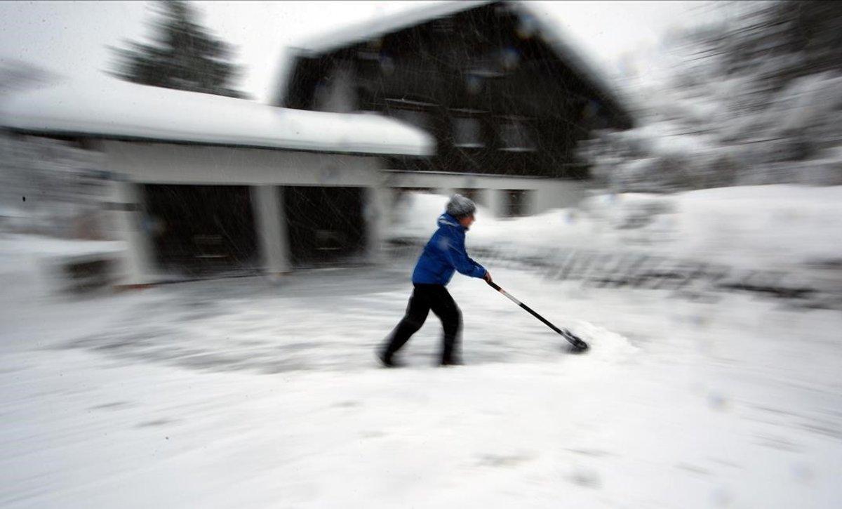 Una mujer quita nieve con una pala en Schaftlach, cerca de Múnic, Alemania.