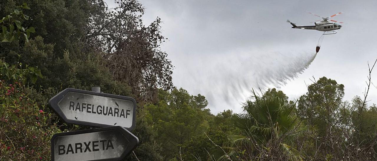 Un helicóptero realiza una descarga en el incendio del pasado mes de agosto en Rafelguaraf. | J.M. LÓPEZ