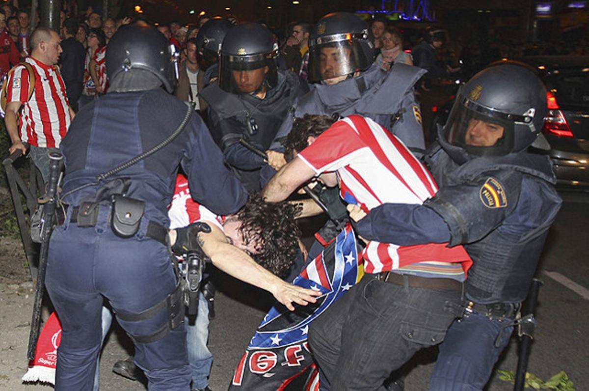 Membres de la policia nacional intenten reduir diversos aficionats de l’Atlètic de Madrid que han protagonitzat altercats durant les celebracions a la plaça de Neptuno, a Madrid, després de vèncer l’Athletic de Bilbao a la final de la Lliga Europa a Bucarest.
