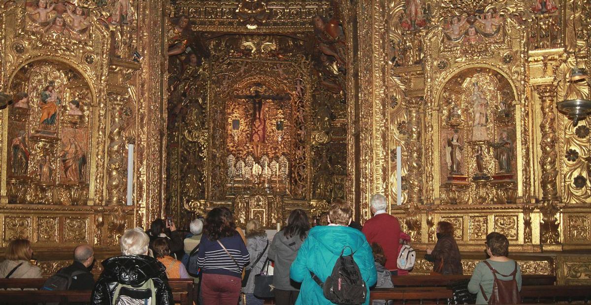Un grupo de turistas contempla el retablo barroco y la talla del Santo Cristo, en una de las principales capillas de la catedral. | |