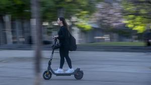 Un patinete circula por la plaza Mestres Maria Rosquellas i Joan Rotger en Badalona.