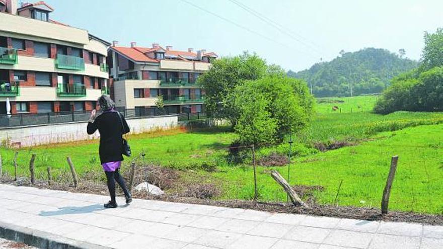 Una mujer camina junto al humedal del Llagu, en Barru (Llanes), sin apenas agua en la actualidad.