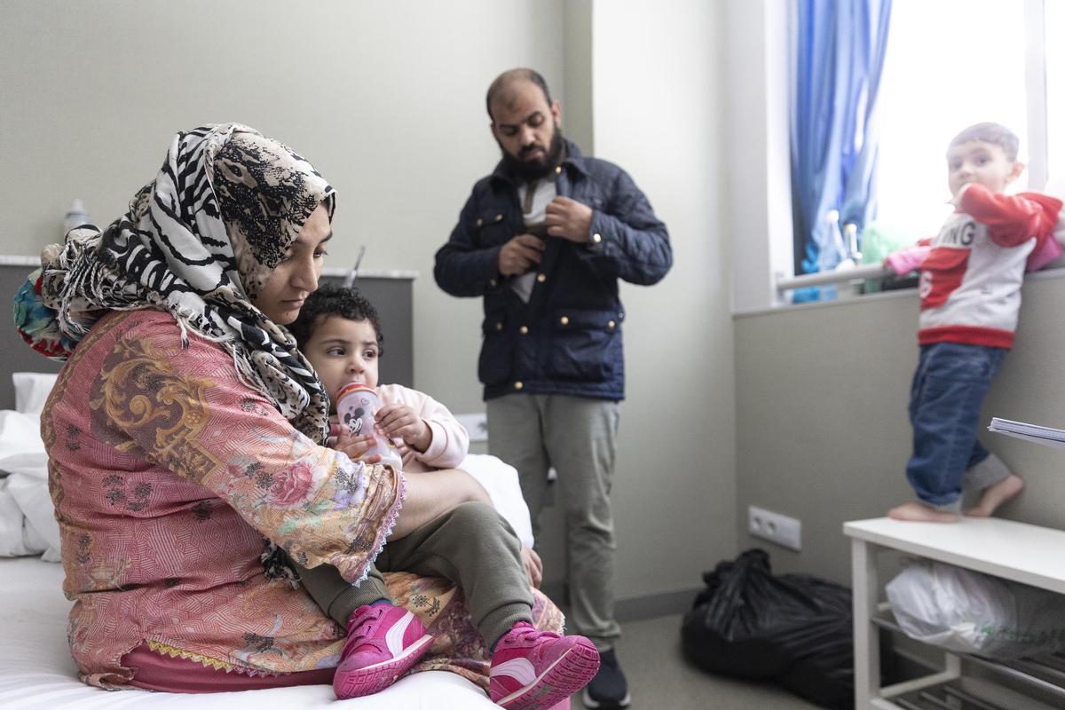 La madre Dua Fatima da el biberón a su hija de un año y medio en la habitación del hostal donde viven.