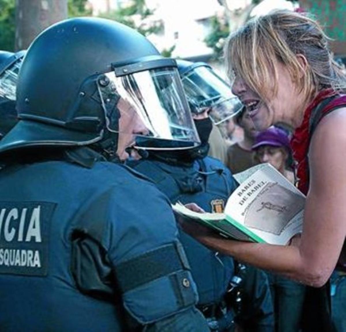 Una manifestant amb un llibre protesta davant d’un mosso, el 15 de juny davant de la Ciutadella.