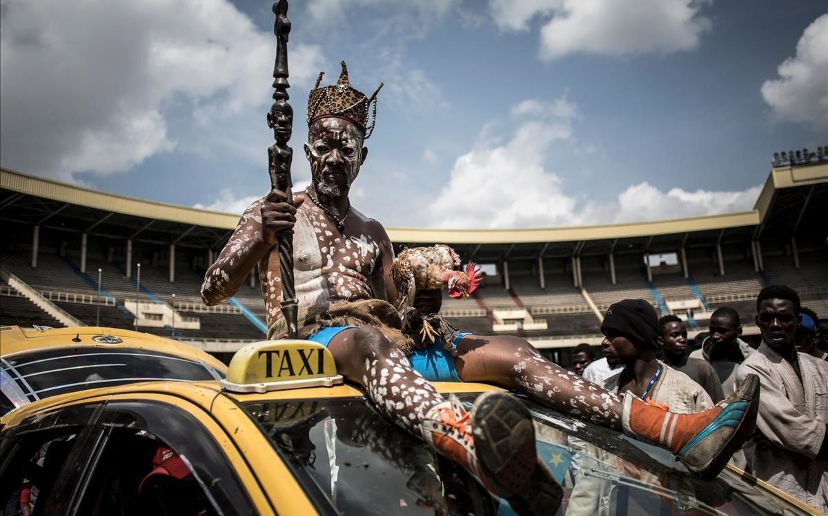 El hombre fetiche de un luchador congoleño se sienta en la parte superior de un automóvil a la llegada al Stade de Martyrs para una exhibición deportiva en Kinshasa.