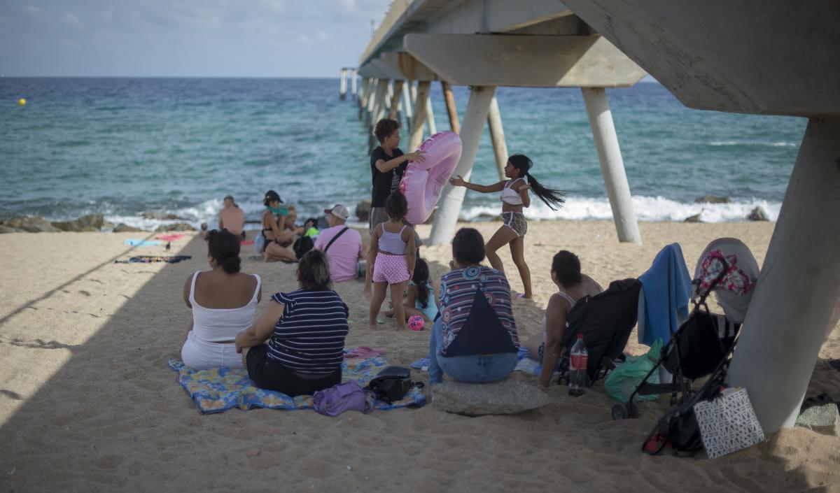 Una familia aprovecha la sombra del Pont del Petroli, en la playa de Badalona