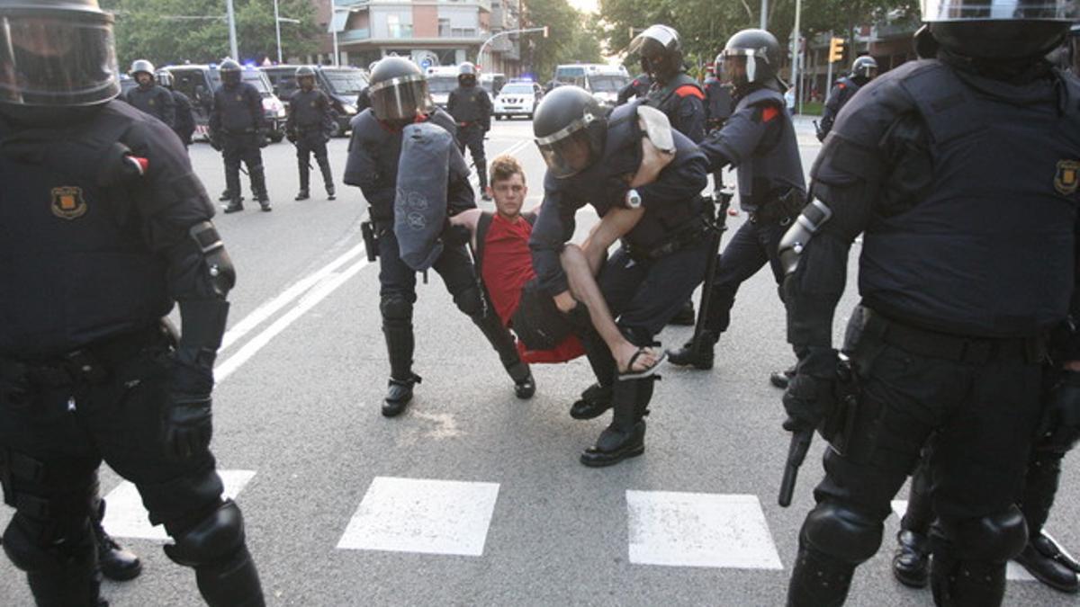 Los Mossos se llevan en volandas a un indignado, en la entrada al parque de la Ciutadella por la calle de Wellington.