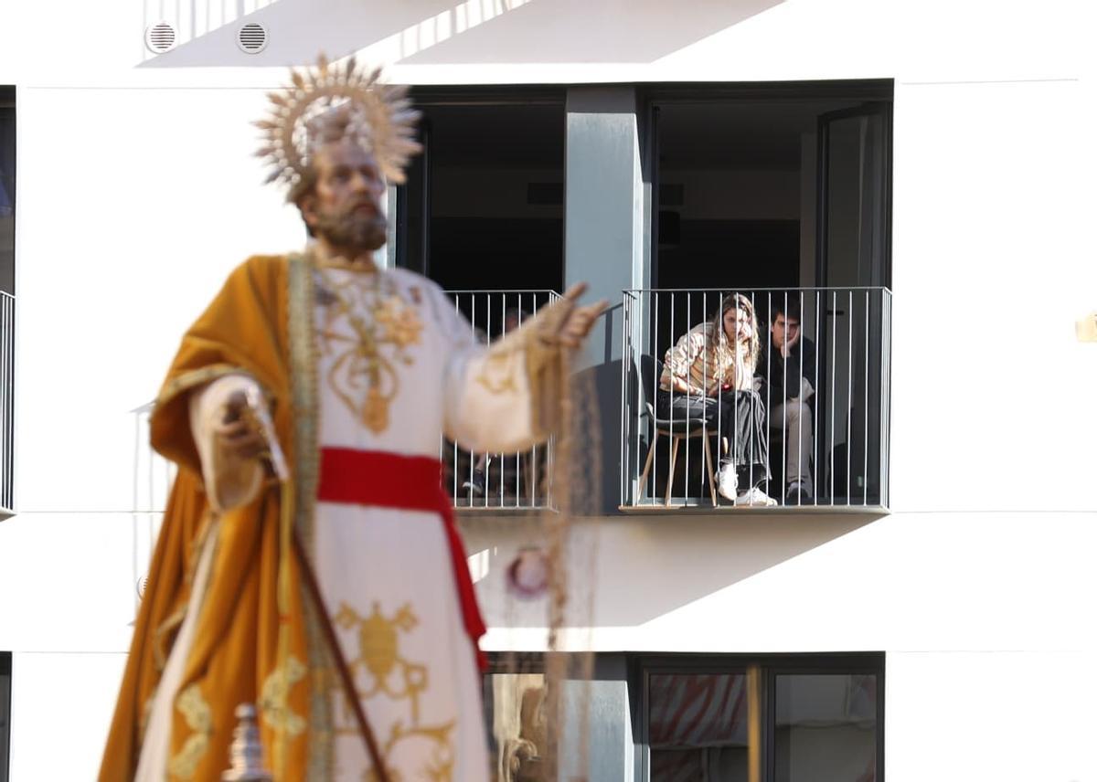 Dos turistas presencian en primera línea una procesión desde el balcón de su apartamento.