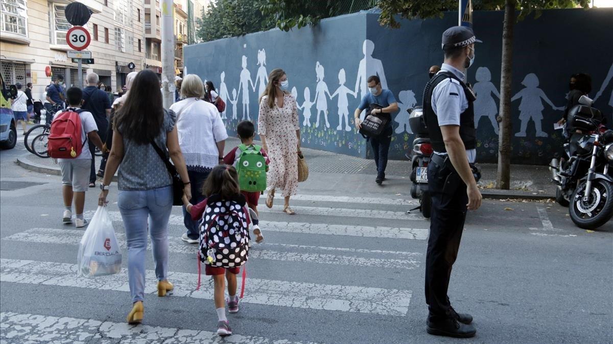 Un policía local regula el tráfico frente al acceso de la escuela Vedruna, en Girona.