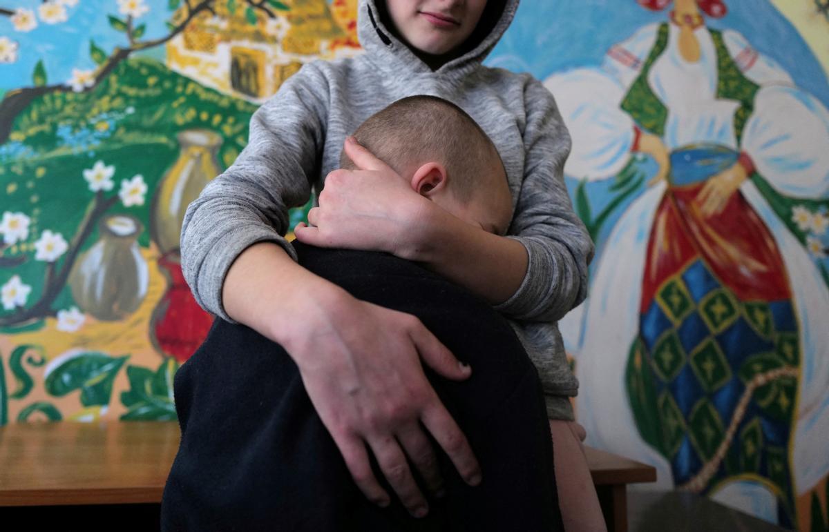 Sophia, de 16 años, a quien le quitaron a su madre viuda junto con sus hermanos, abraza a su hermano Mykhaylo, de 8, en un refugio estatal en Lviv, Ucrania.