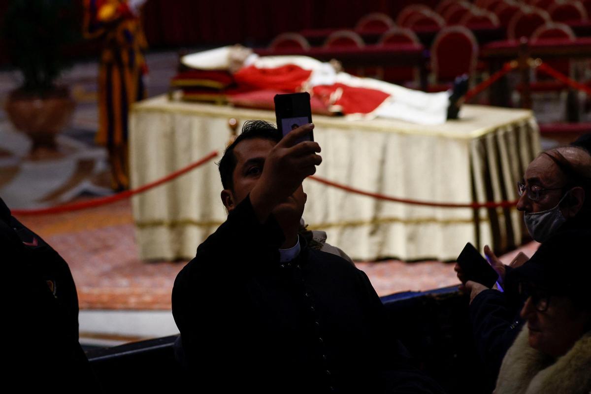 Un hombre  se hace un selfie  mientras los fieles rinden homenaje al ex Papa Benedicto en la Basílica de San Pedro en el Vaticano.