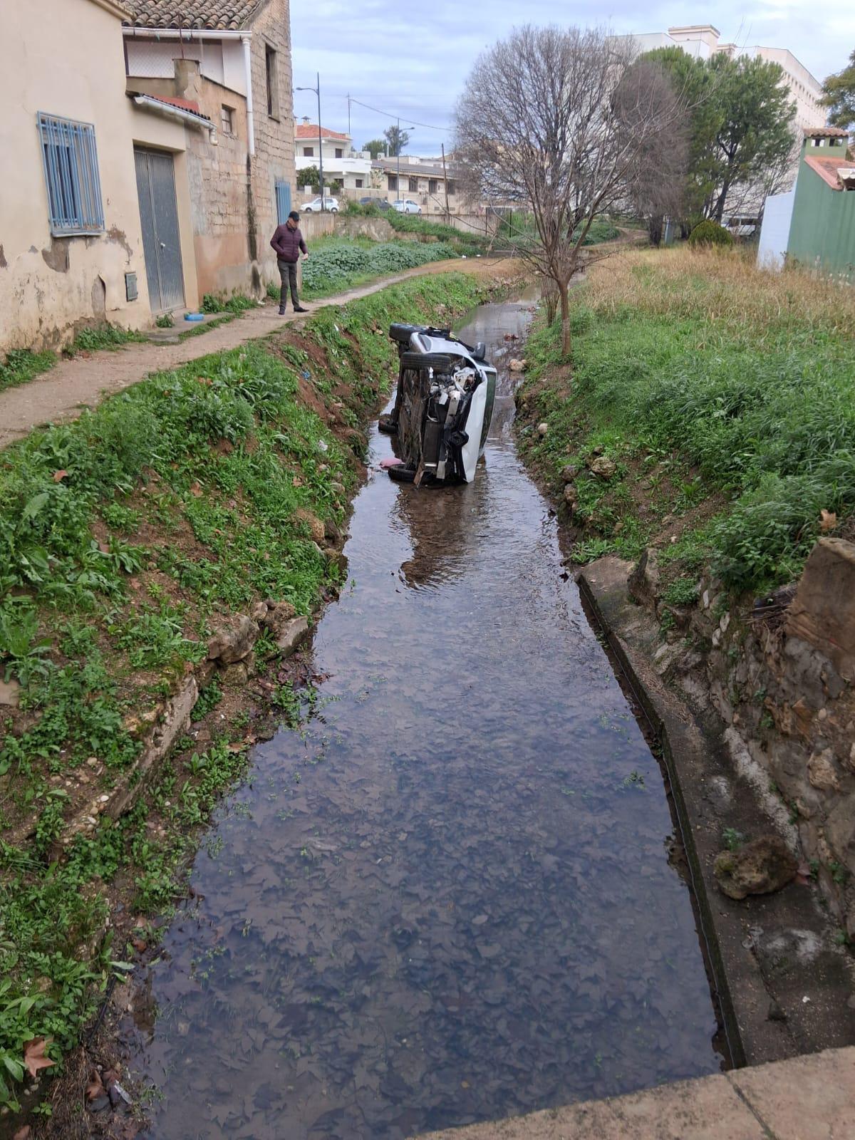 Un hombre observa el coche que acabó en el ríu Sants de Canals.