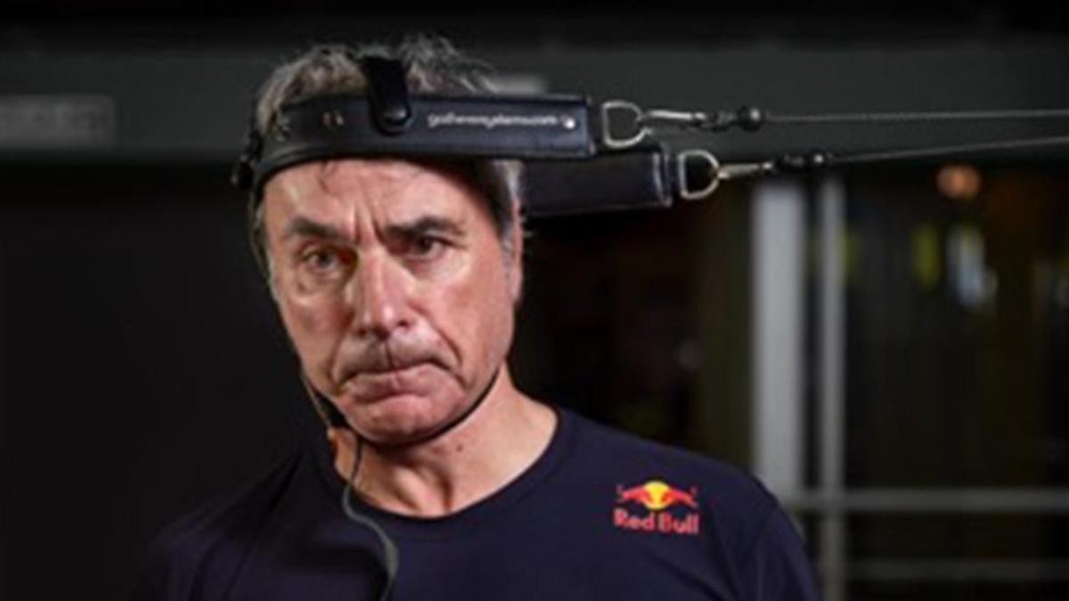 Carlos Sainz con el rostro desencajado, haciendo ejercicios para fortalecer su cuello.