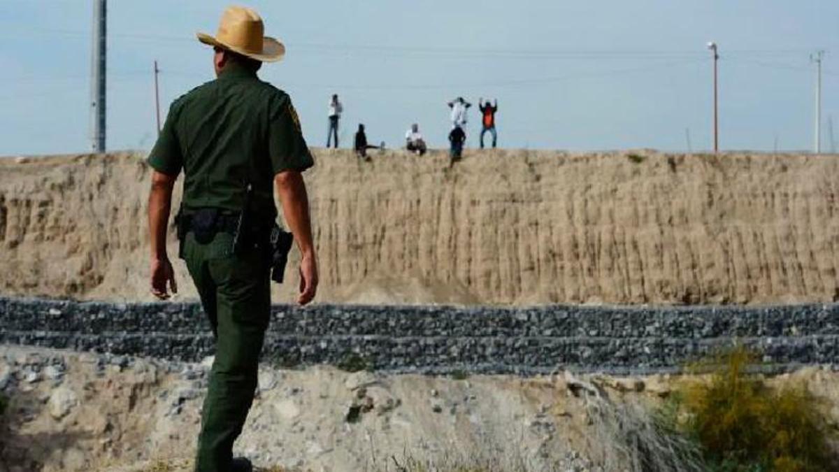 Un agent de fronteres dels EUA a Texas observa persones que miren de travessar des del cantó mexicà.