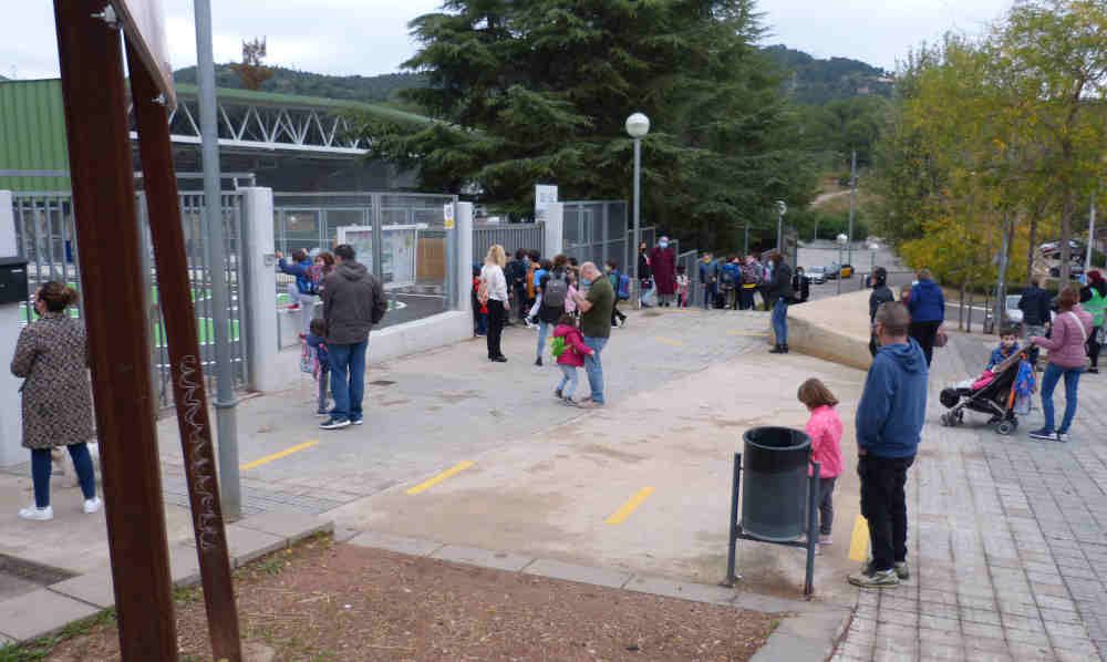 Un grupo de personas espera a la salida de un colegio en Gavà