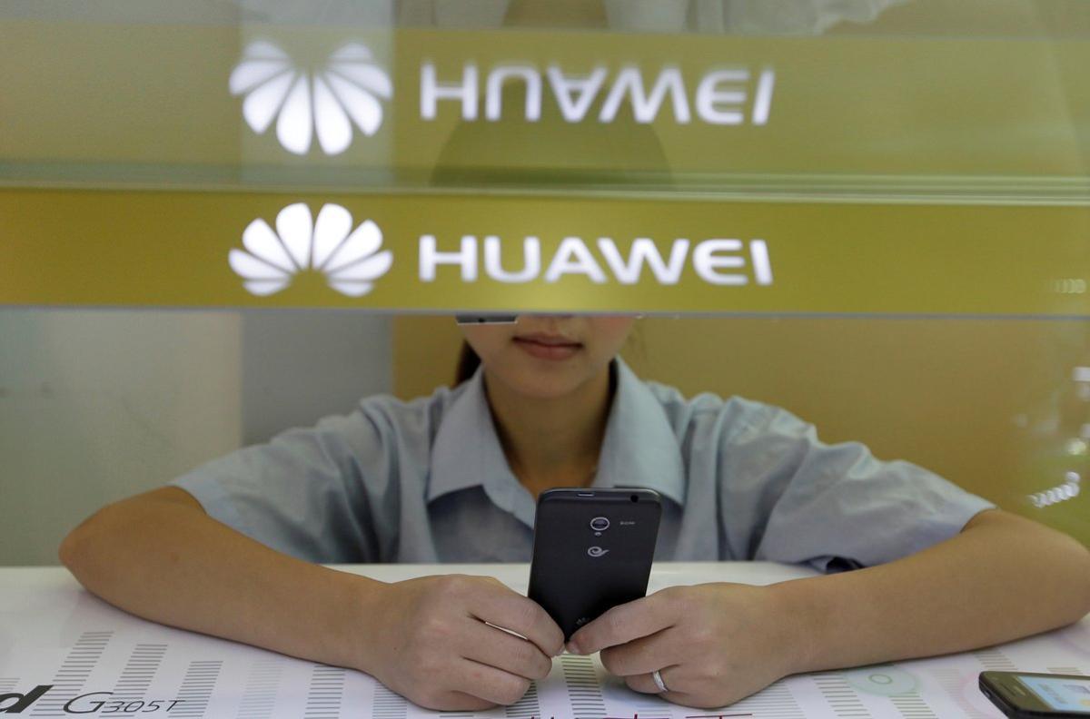 A sales assistant looks at her mobile phone as she waits for customers behind a counter at a Huawei booth in Wuhan, Hubei province, October 10, 2012. REUTERS/Stringer/File Photo  CHINA OUT. NO COMMERCIAL OR EDITORIAL SALES IN CHINA