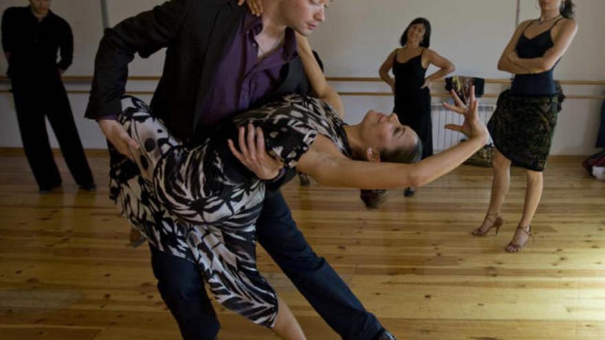 Sergei Nifontov practica uno de los pasos de baile con Tamara Arroyo, una de las alumnas, ante la atenta mirada del resto de la clase.  RAFA ARJONES