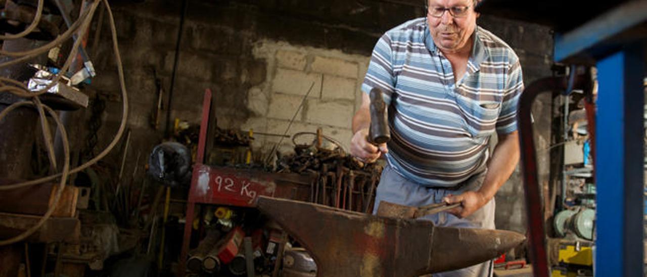 Francisco Alonso enseña el trabajo con el yunque en el taller de su casa en la localidad de Antigua y detrás la fragua con la que trabajaba.