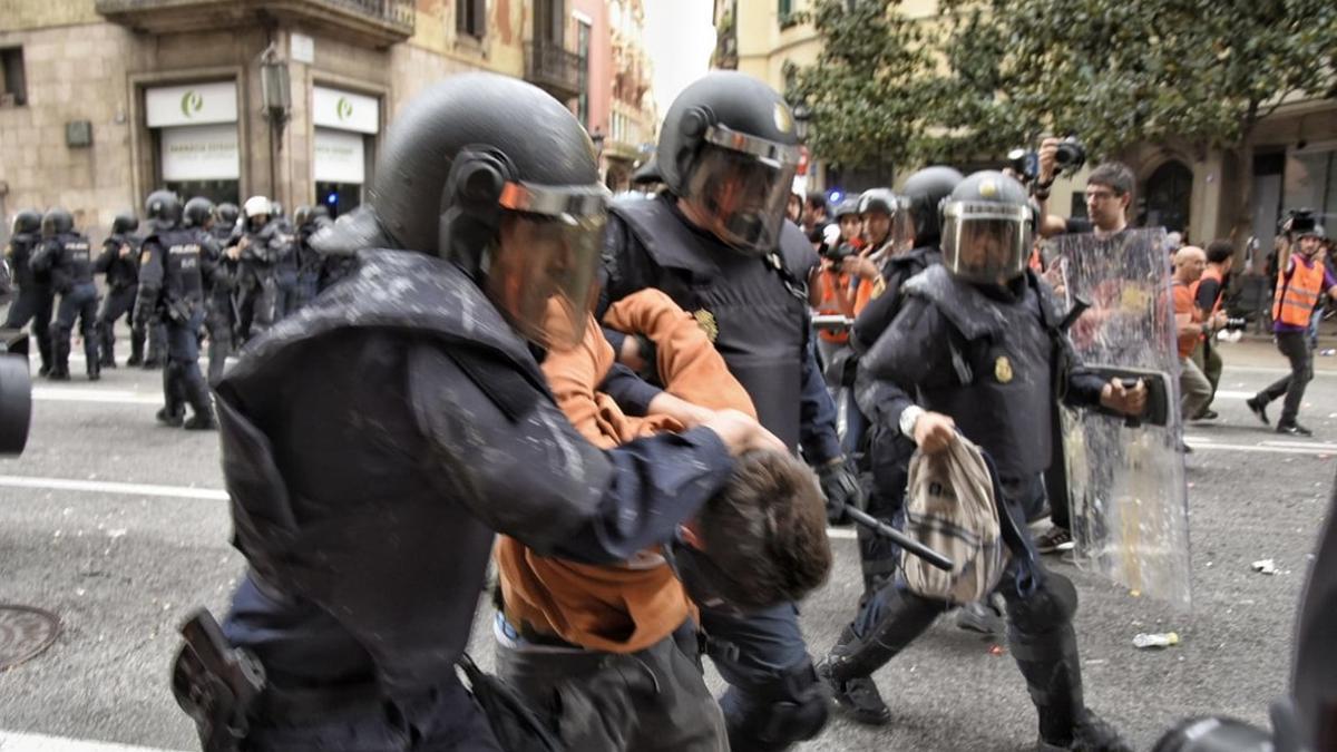 Dos policías con uno de los manifestantes detenidos en Via Laietana