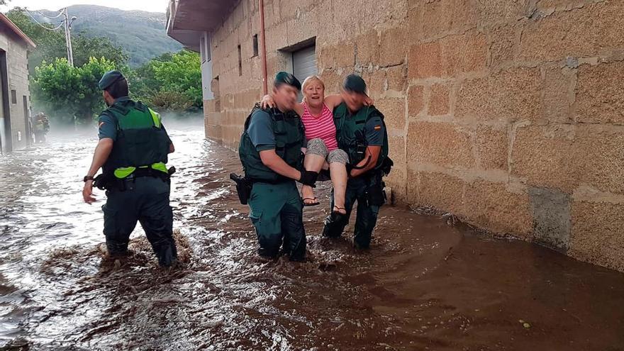 Agentes de la Guardia Civil trasladan a una vecina de Infesta, en Monterrei (Ourense), tras la riada. Inundaciones, granizada y un reguero de incidencias es el saldo de este lunes de julio en Ourense, donde se activó la alerta naranja en la zona de montaña Ourense.