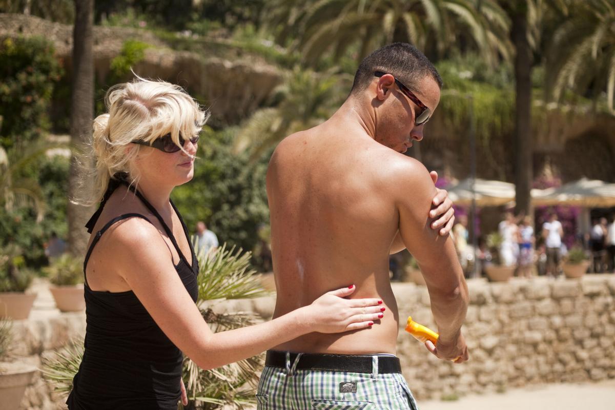Gente protegiéndose del sol con crema solar en el Parc Guell de Barcelona.