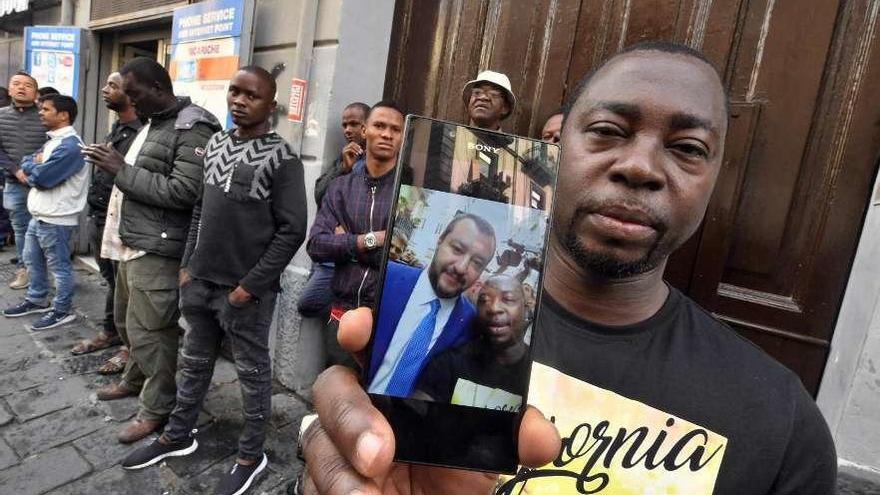 Un inmigrante muestra una foto con el xenófobo Salvini, de visita en Nápoles. // Efe