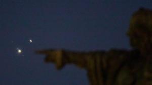 El monumento de Colón de Barcelona, este lunes, con la conjunción máxima de Júpiter y Saturno (arriba)