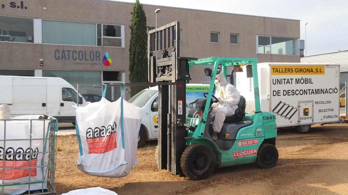 Un operari mou una saca amb restes de fibrociment amb un toro mecànic en la zona habilitada pel Consell Comarcal del Baix Empordà