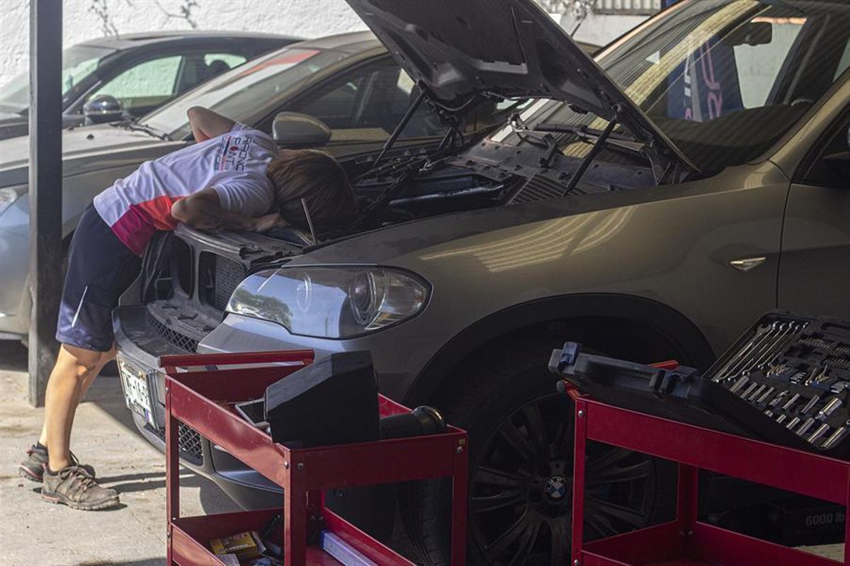 Una mujer revisa el motor de su coche