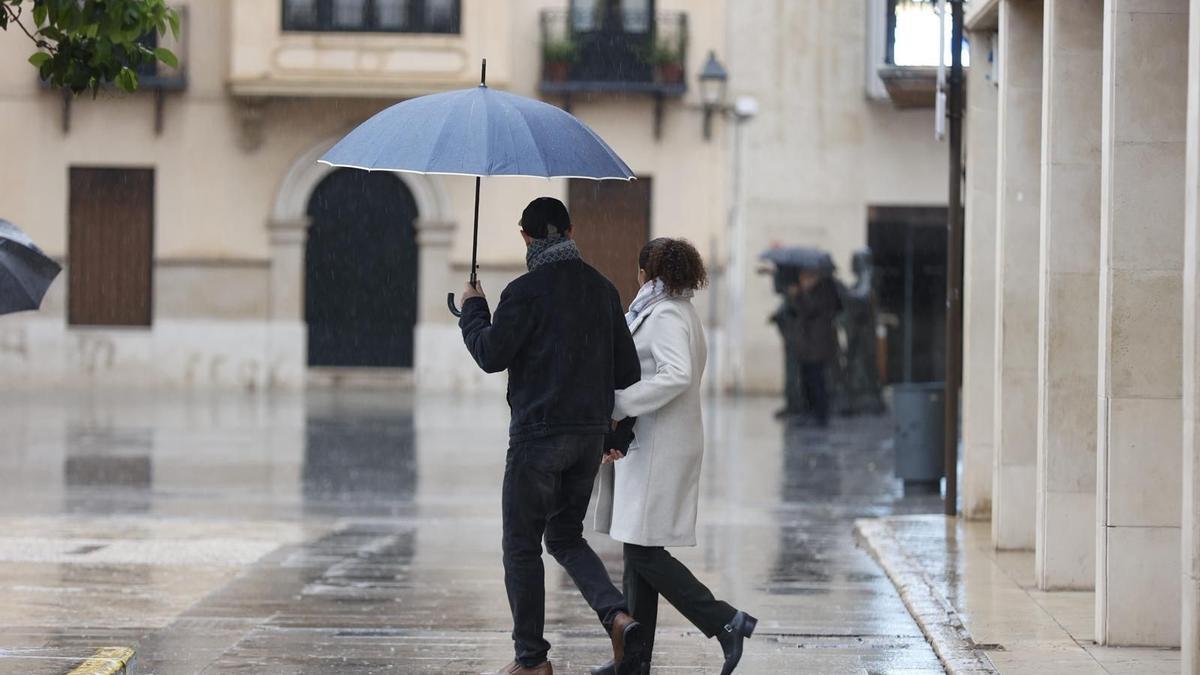 Una pareja pasea bajo la lluvia por el centro de Elche este dia de Navidad
