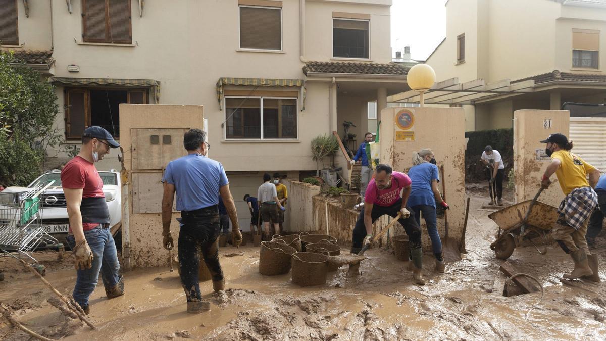 Limpieza de una calle de Paiporta inundada de lodo.