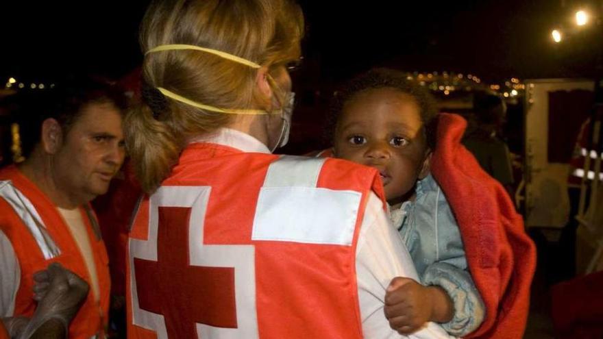 Una sanitaria de Cruz Roja atiende a un niño llegado en una patera.