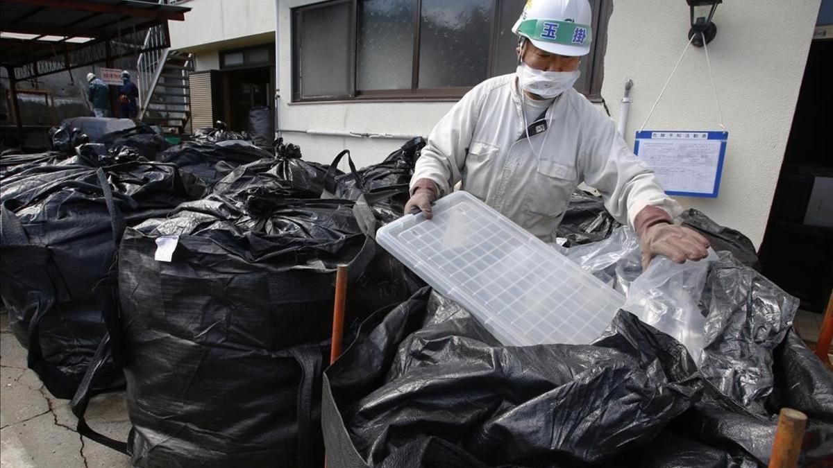 Un trabajador mete en una bolsa residuos radiactivos en una casa de Minamisoma.